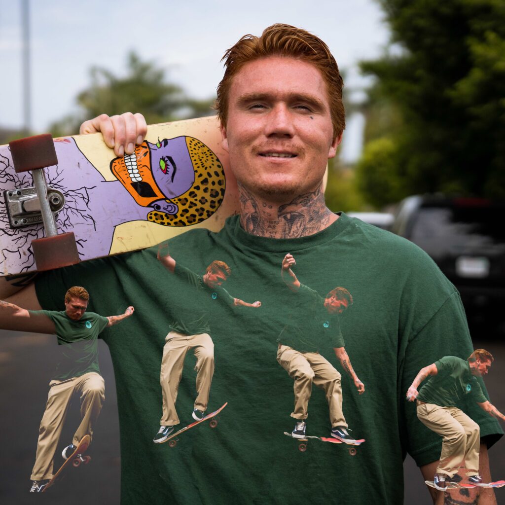A man with red hair, known as Jordan ‘Red’ T., holds a skateboard over his shoulder. His shirt features a sequence showing him skateboarding, and the skateboard has colorful, artistic graphics. Trees and a black car are in the background.